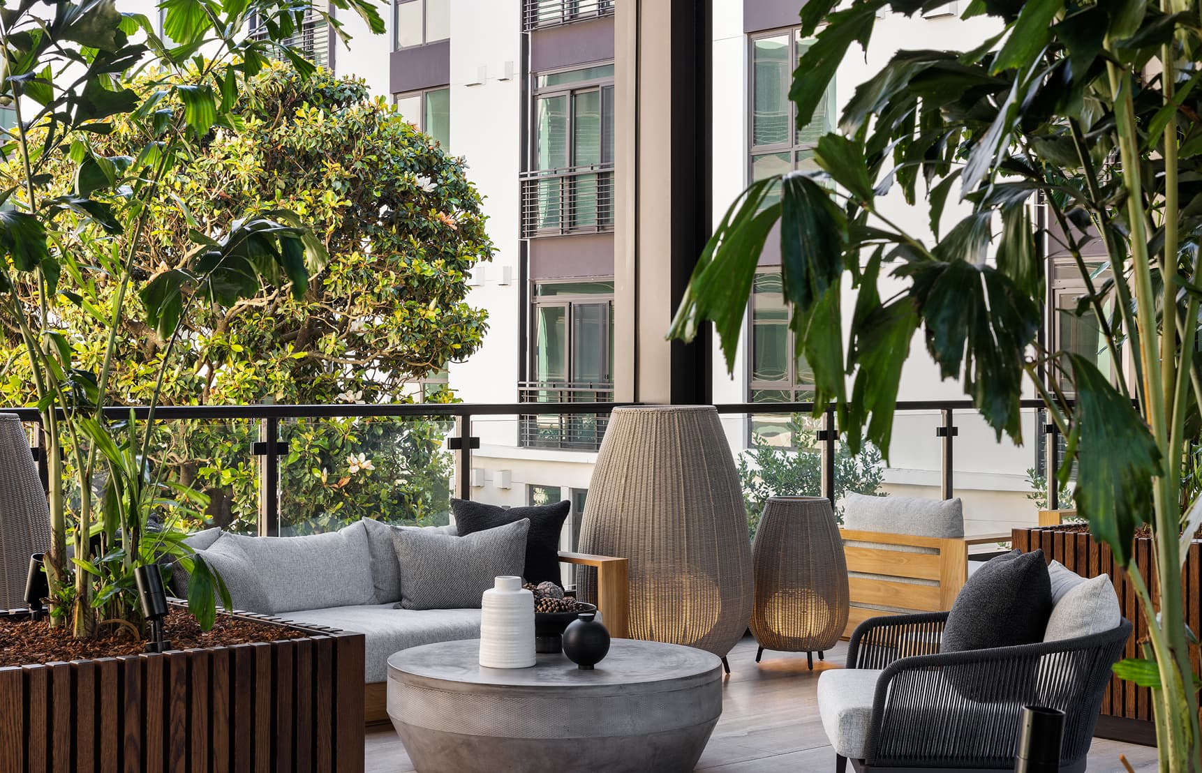 Luxury apartment patio at Bristol on Treasure Island featuring modern outdoor lounge seating, lush greenery, and contemporary design within a residential courtyard in San Francisco.
