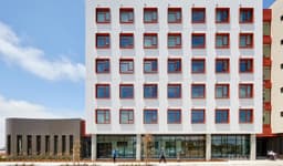 Six-story residential apartment building at Maceo May on Treasure Island, with a modern façade, large windows, and landscaped walkways and greenery in the foreground.